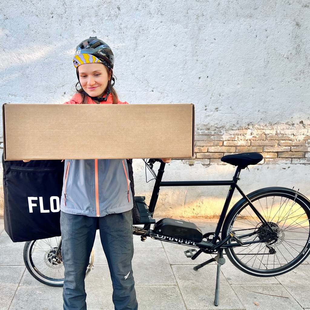Mensajera de Florbox en bicicleta con una caja llena de flores 